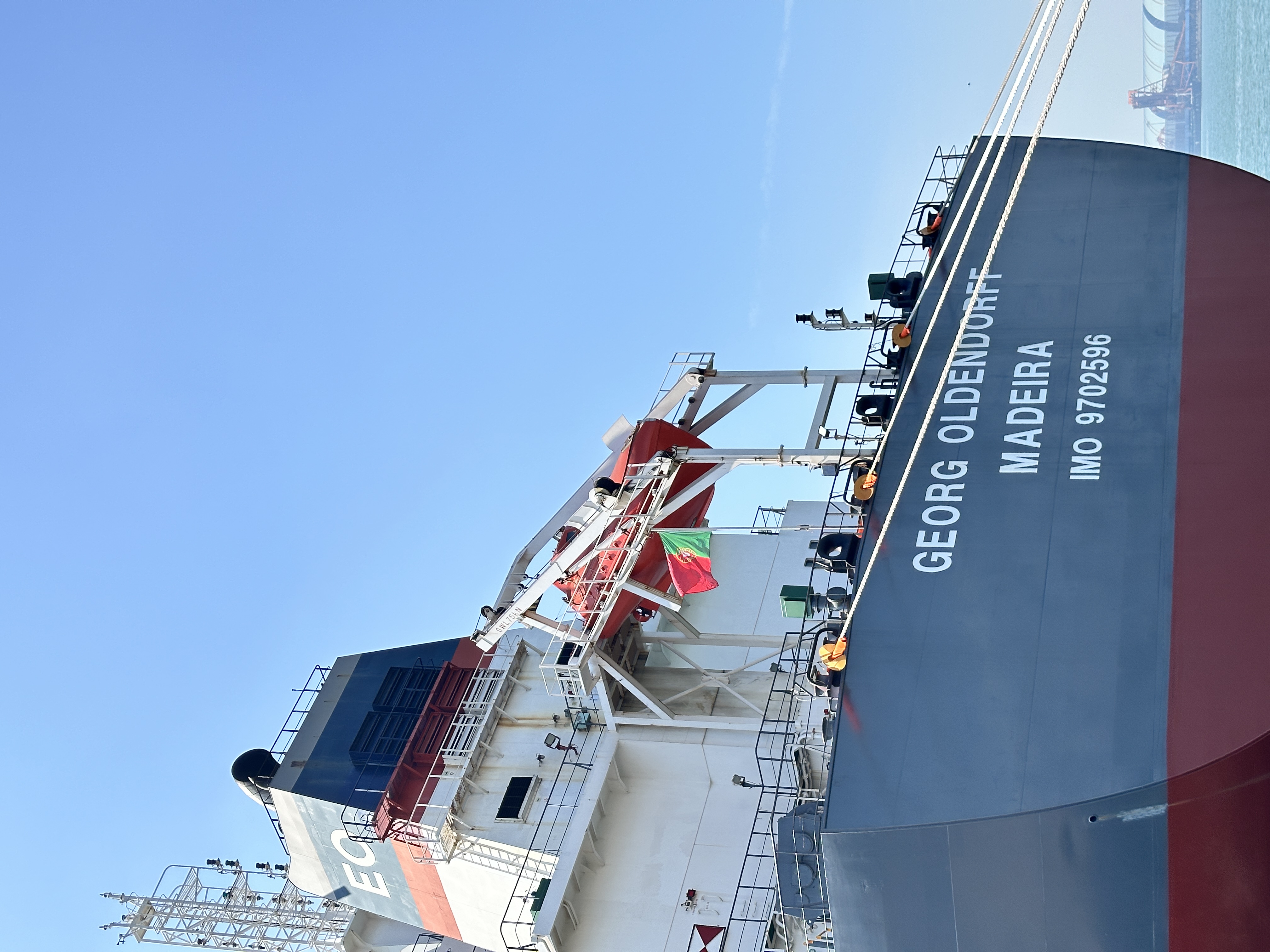 Dry bulk export terminal and vessel scene showing longer-haul freight pressure for cementitious materials